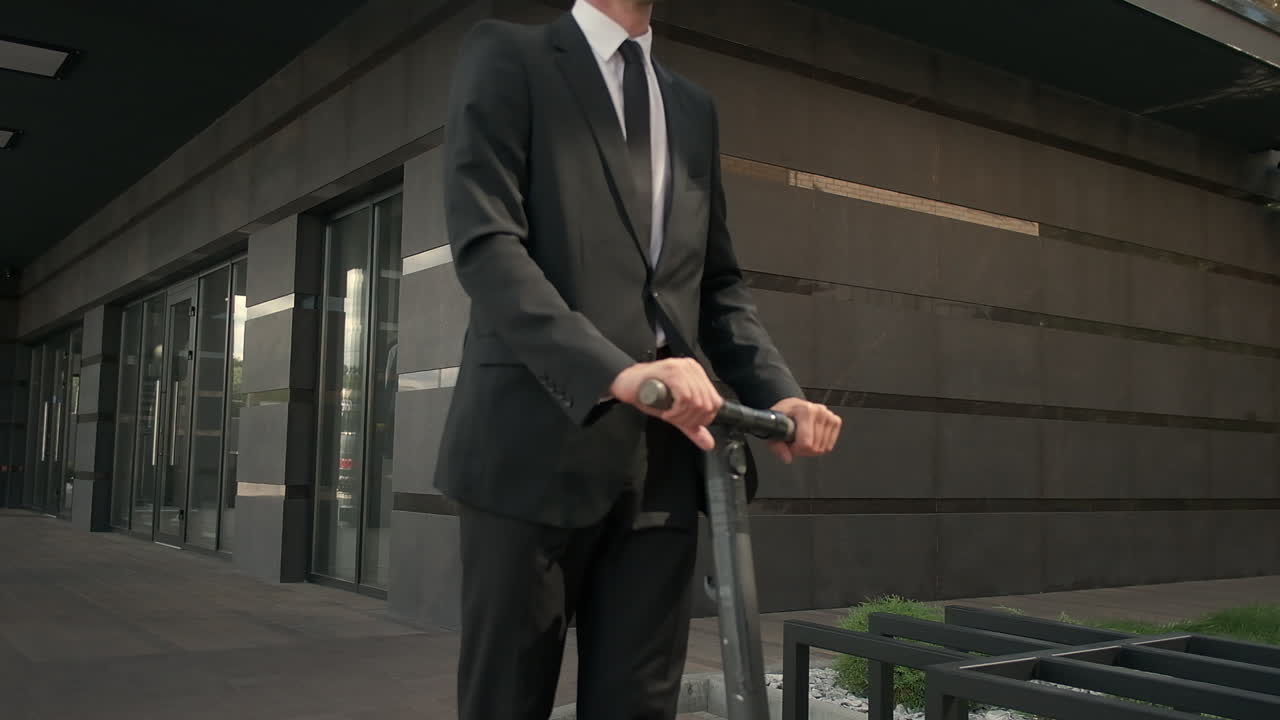 un hombre de negocios montando un scooter eléctrico fuera de un edificio moderno