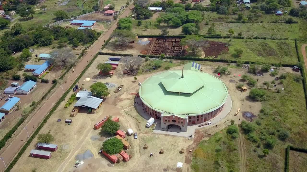 Aerial view of missionaries circular church large temple with green roof in Moroto Town, Karamoja, Uganda, showcasing the development of religious infrastructure in the region, drone establishing shot