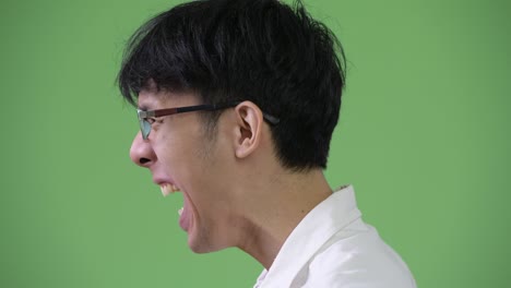 profile view of angry young asian businessman screaming