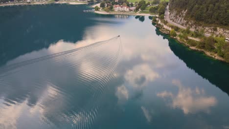 el dron cae siguiendo un pequeño barco en el lago ledro, trentino, val di ledro en el norte de italia.
