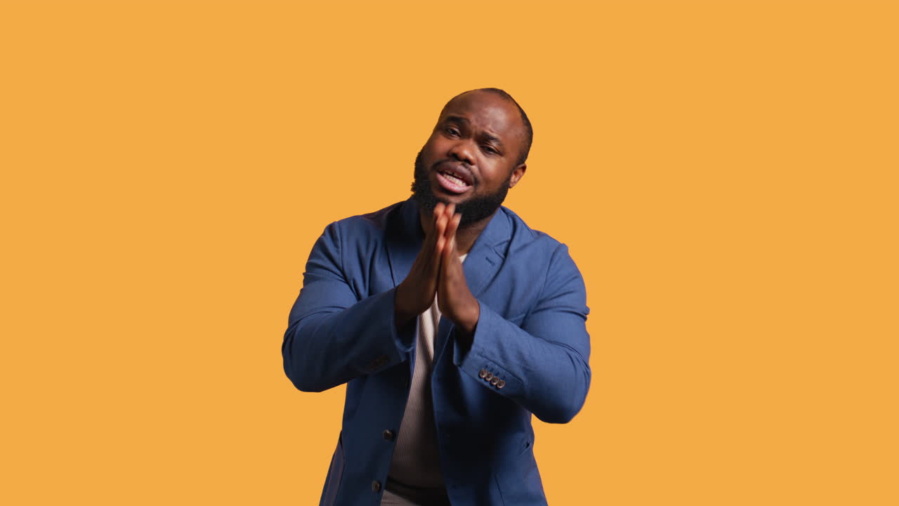Man putting hands together in begging gesture, making wish, studio background