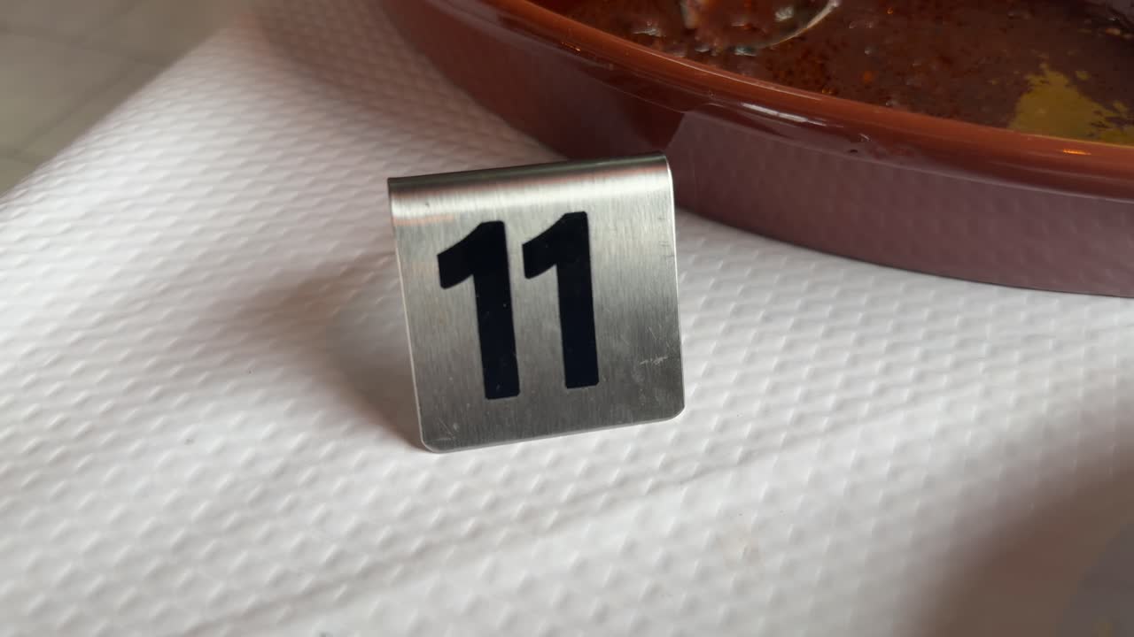Cartello da tavolo in metallo con numero undici su tovaglia bianca in ristorante