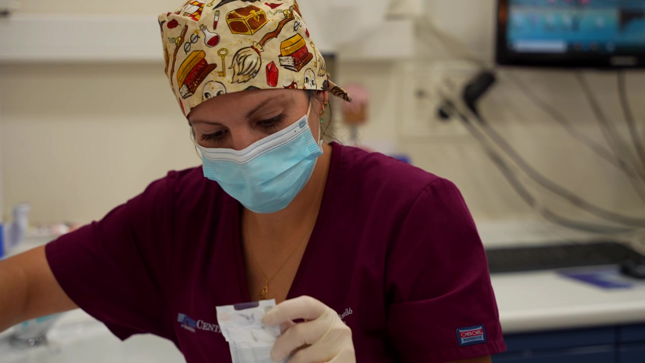 Professionista del settore dentale che prepara attrezzature sterili per una prossima procedura di igiene orale.