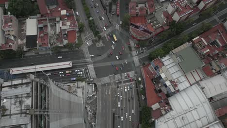 Rising-Mexico-City-aerial:-Urban-traffic-driving-on-busy-street-below