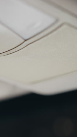vista en primera persona de una mujer abriendo una caja del techo del coche y colocando gafas en el interior por la noche. la escena destaca su mano con uñas pintadas de negro mientras interactúa con la caja del tejado del coche