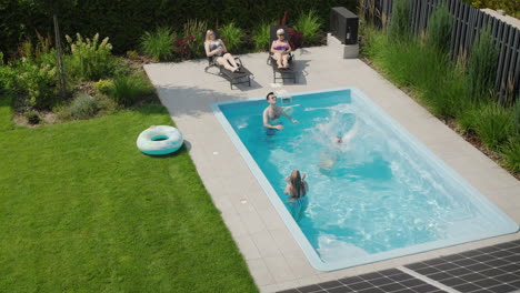 una mujer salta a la piscina. vacaciones familiares divertidas en el patio trasero de una casa en un caluroso día de verano