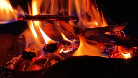 Closeup-of-campfire-burning-with-orange-flame-glowing-at-night