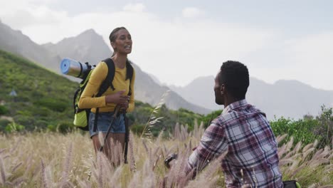 una pareja afroamericana se da los cinco mientras caminan por las montañas.