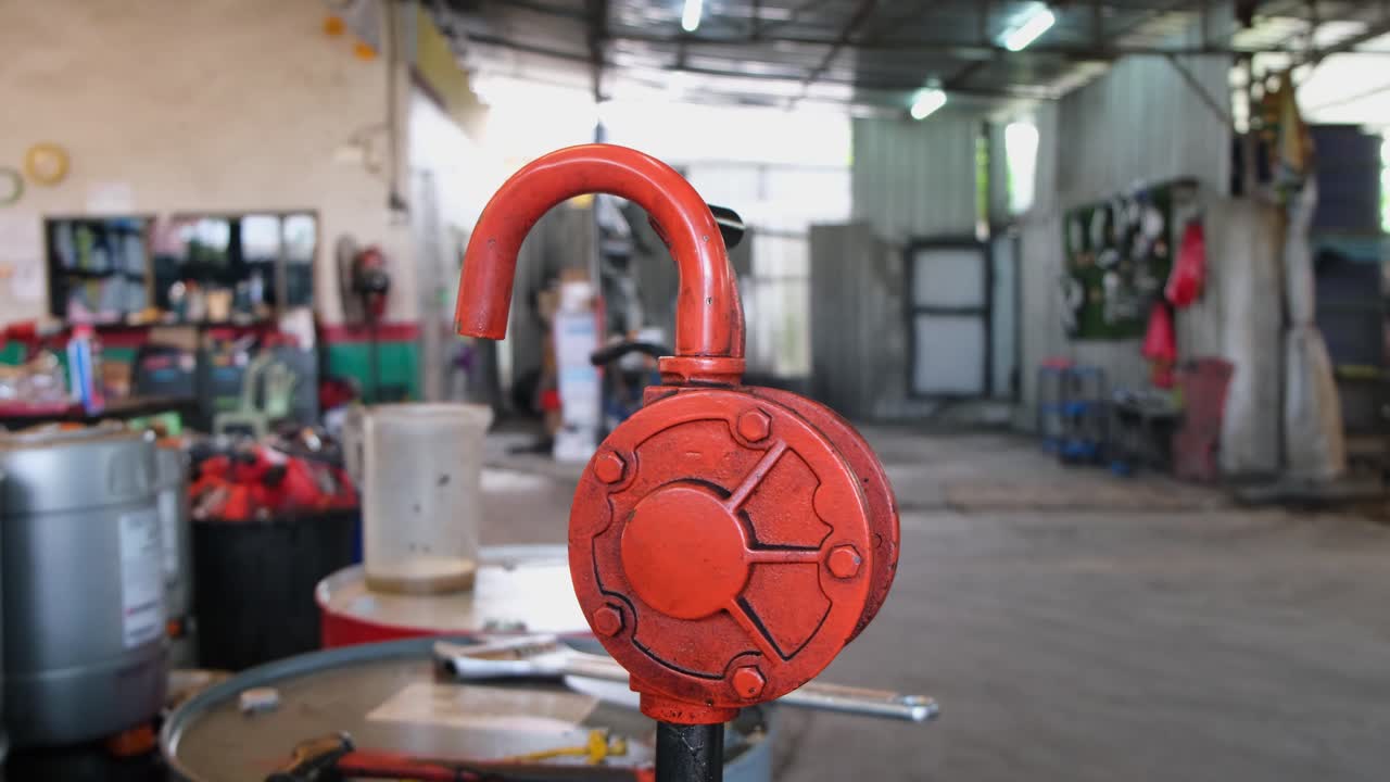 bomba de manivela vista mientras la cámara se desliza hacia la izquierda revelando el escenario en este taller de reparación de automóviles, bangkok, tailandia