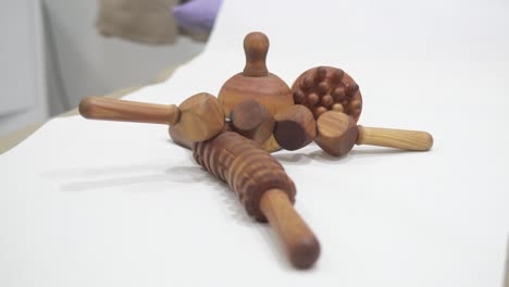 물리치료 클리닉의 마사지 침대 테이블에 배치된 수동 심층 조직 마사지 요법에 사용되는 나무 마사지 세트를 닫습니다.
