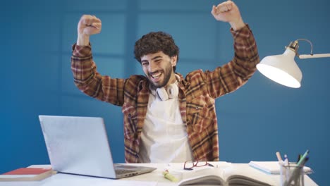 young student man completing his homework or a creative project and experiencing joy.