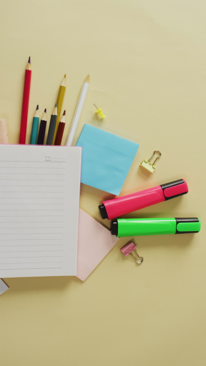 vídeo vertical de notas, lápices de colores, marcadores y tarjetas de correo que se encuentran en la superficie amarilla