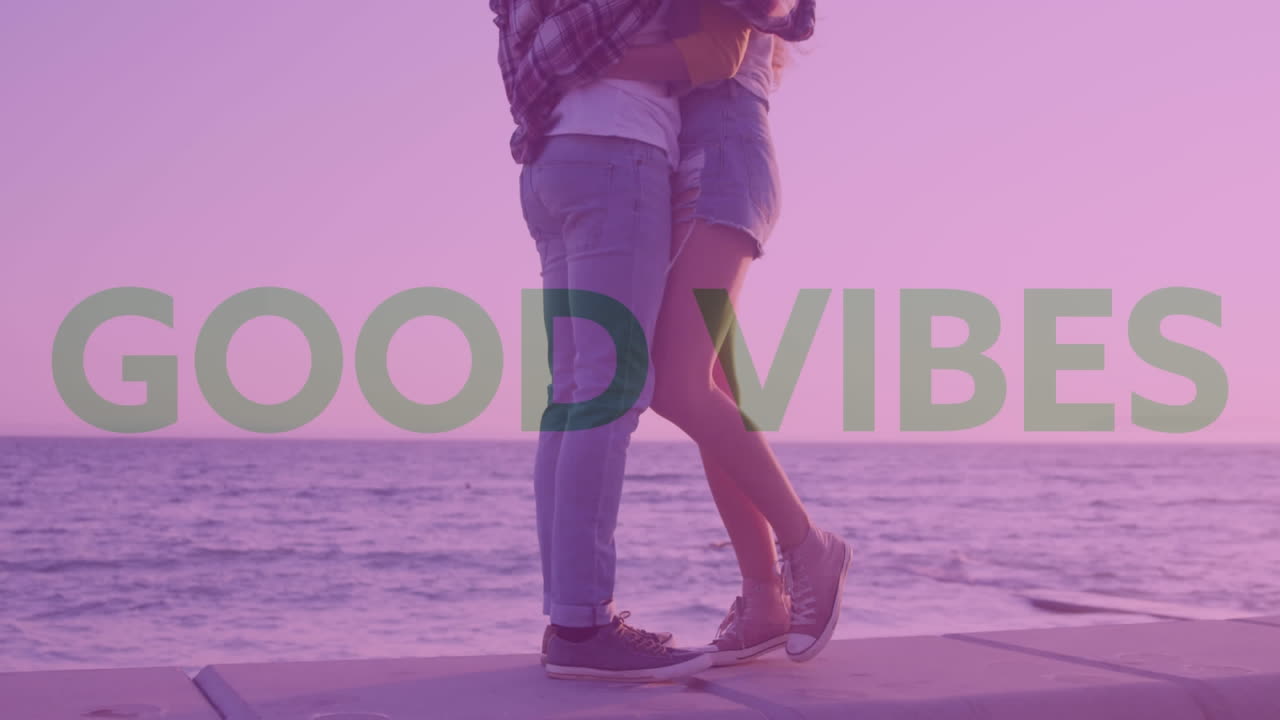 múltiples textos de buenas vibraciones contra la sección baja de una pareja caucásica abrazándose cerca del mar