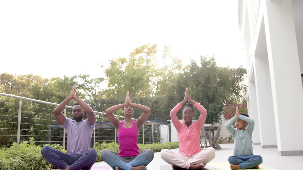 felices padres afroamericanos, hijo e hija practicando yoga en un jardín soleado, en cámara lenta.