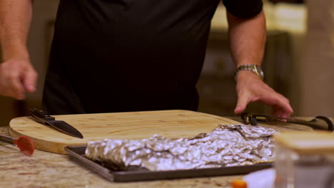 hombre caminando a la tabla de corte con costillas de barbacoa envueltas en papel de aluminio