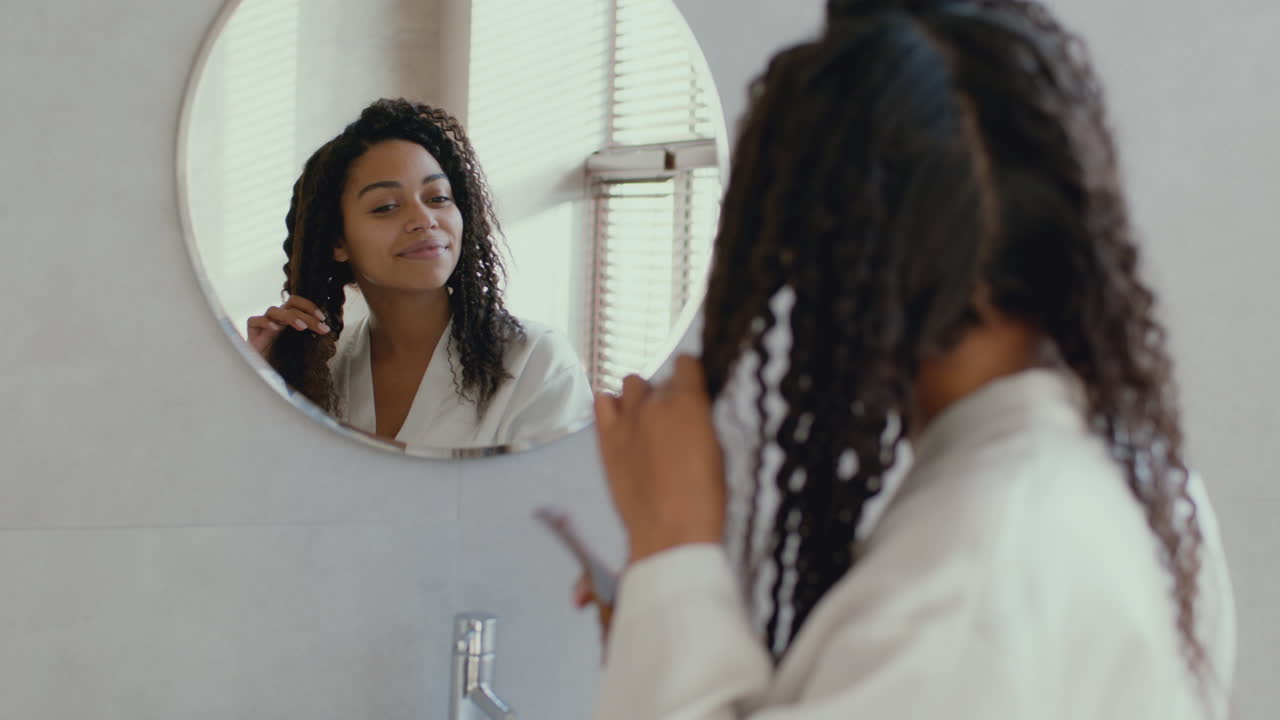 Donna che si pettina i capelli ricci in bagno