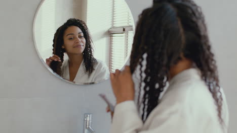 woman brushing her curly hair in the bathroom
