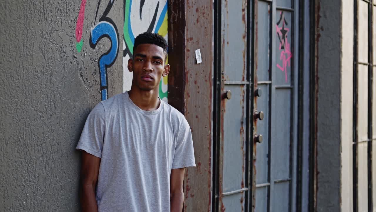 joven apoyado en una pared cubierta de graffiti