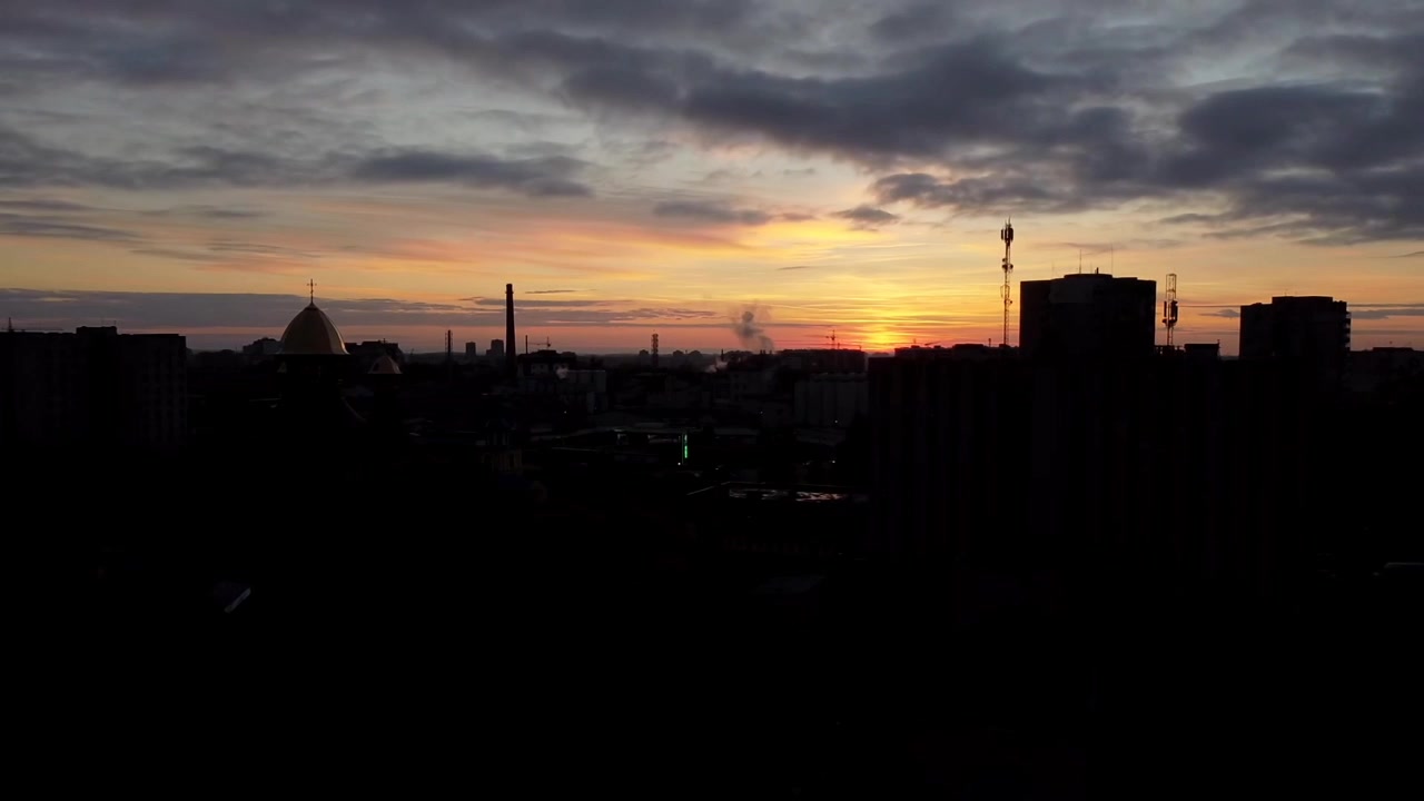 Вид с воздуха на дрон, летящий над городом. Закат в небе.