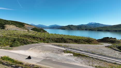 biker travelling on village rural road overseeing blue lake and mountains