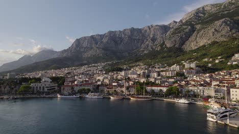 makarska coastal town with mountains, marina, and clear sea at golden hour
