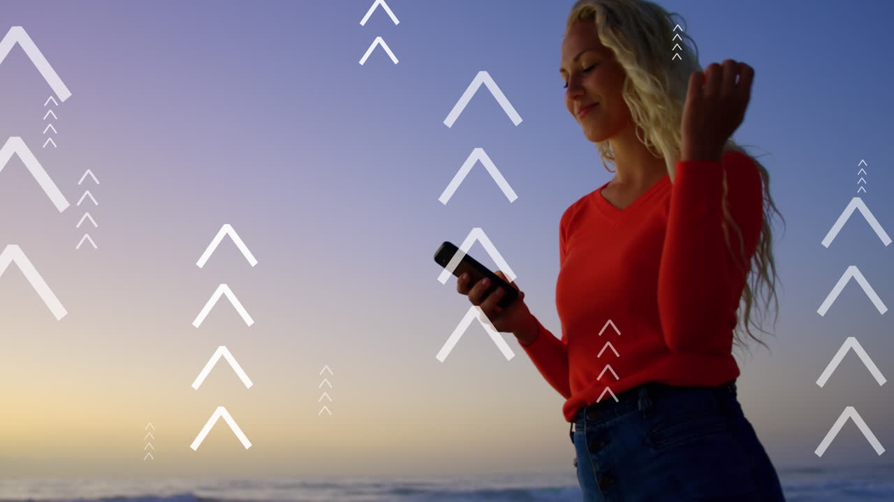 animación de flechas sobre una mujer caucásica feliz usando un teléfono inteligente al atardecer