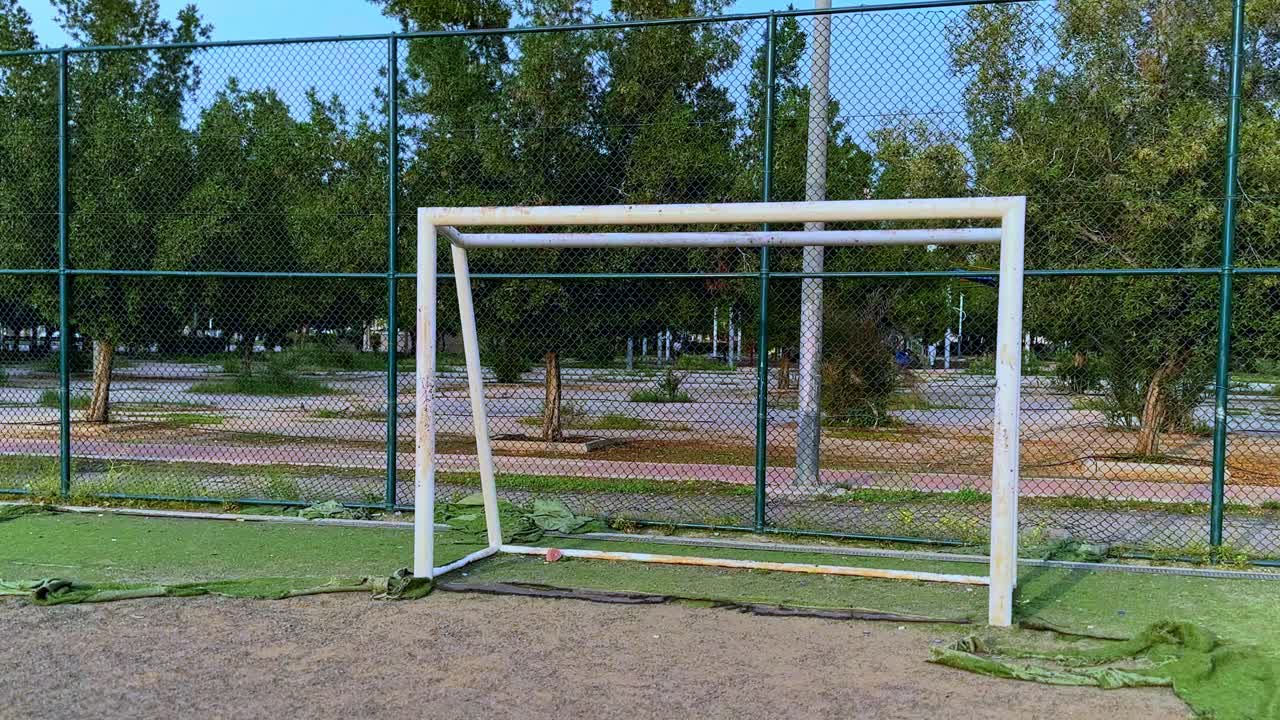 A weathered soccer goal post stands in a quiet park sports area, captured in 4K. Ideal for sports, recreation, community, or outdoor lifestyle themes in storytelling or commercials.