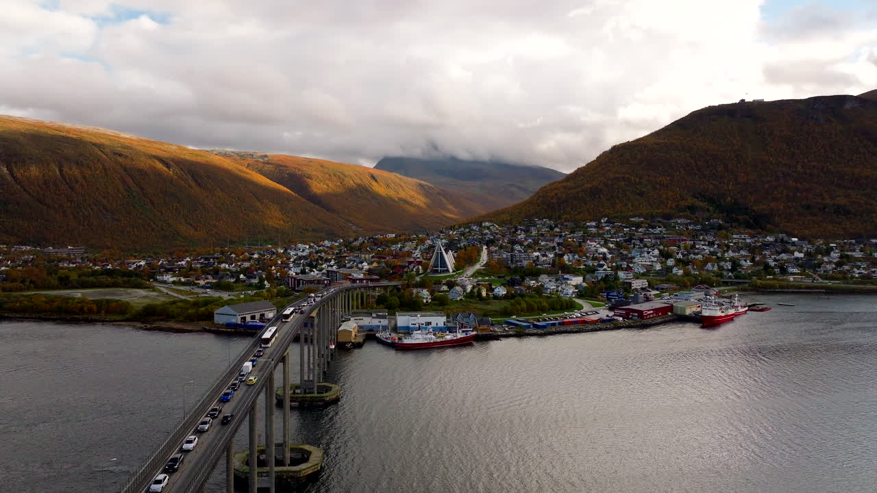 Traffic over Tromso bridge toward Arctic Cathedral with mountains in fall colors