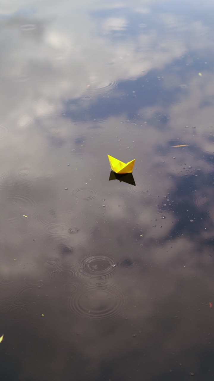 A paper boat floating on the river. Origami ship sailing. Vertical video