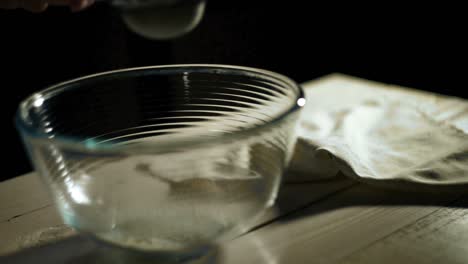 man hand pours flour through sieve into glass bowl. food ingredient