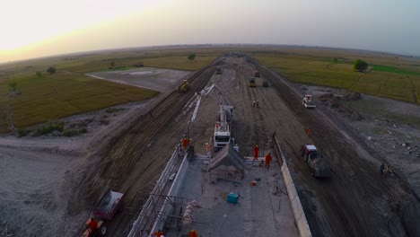 Aerial-view-of-Under-constructed-bridge-with-heavy-duty-trucks-and-machinery-in-the-farm-area