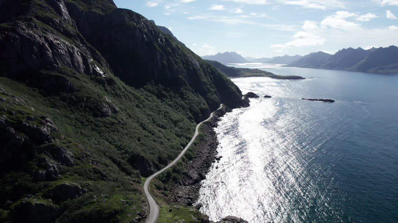 toma aérea de una carretera remota al borde de una montaña escarpada a lo largo de la costa rocosa del norte de noruega cerca del pueblo de nyksund