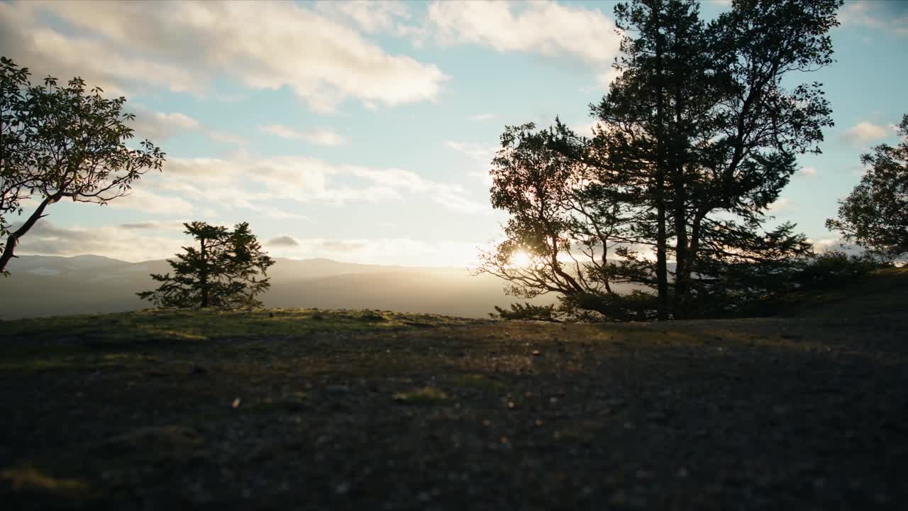 Push-in cinematografico di una valle montana al tramonto, cieli luminosi e cime innevate che creano un paesaggio alpino sereno ed epico