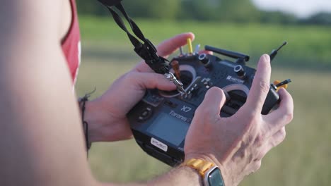 FPV-Drohnenflug:-Mann-Steuert-Drohne-Mit-Schwarzer-Fernbedienung,-Die-An-Einem-Riemen-Gehalten-Wird