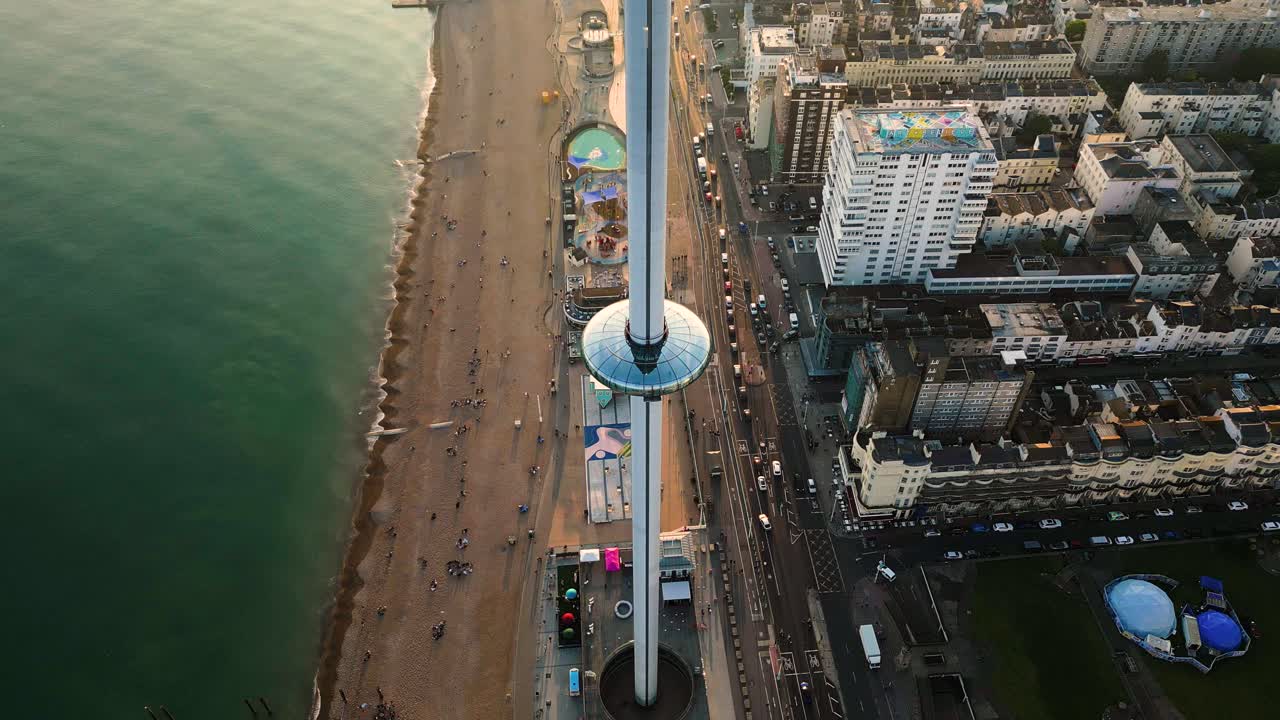 Vista Aerea su Brighton i360 al Tramonto con Traffico sul Lungomare dalla Spiaggia ai Tetti della Città