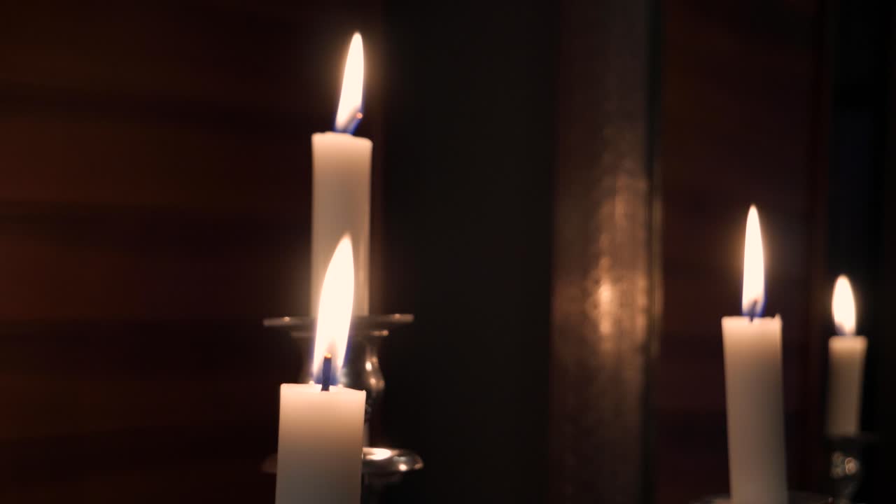 Ripresa a mano intermedia di alcune candele su un candelabro d'argento con pareti in legno e uno specchio sullo sfondo