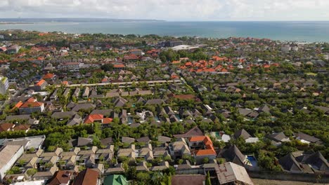 Aerial-view-of-Canggu-Village,-Badung-Regency,-Bali,-highlighting-traditional-Balinese-architecture,-lush-greenery,-and-a-scenic-horizon