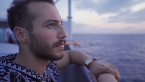 the young man traveling on the ship watches the sea.