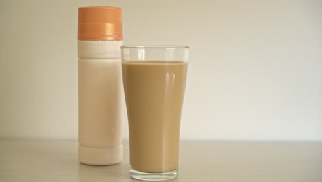Vaso de café con leche con botellas de café listas para beber en la mesa