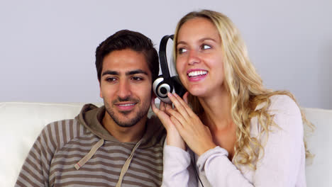 una pareja linda escuchando música juntos en el sofá.