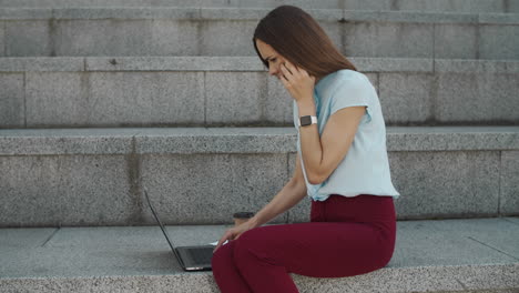 Business-woman-reading-good-news-on-laptop.-Female-worker-talking-on-smartphone