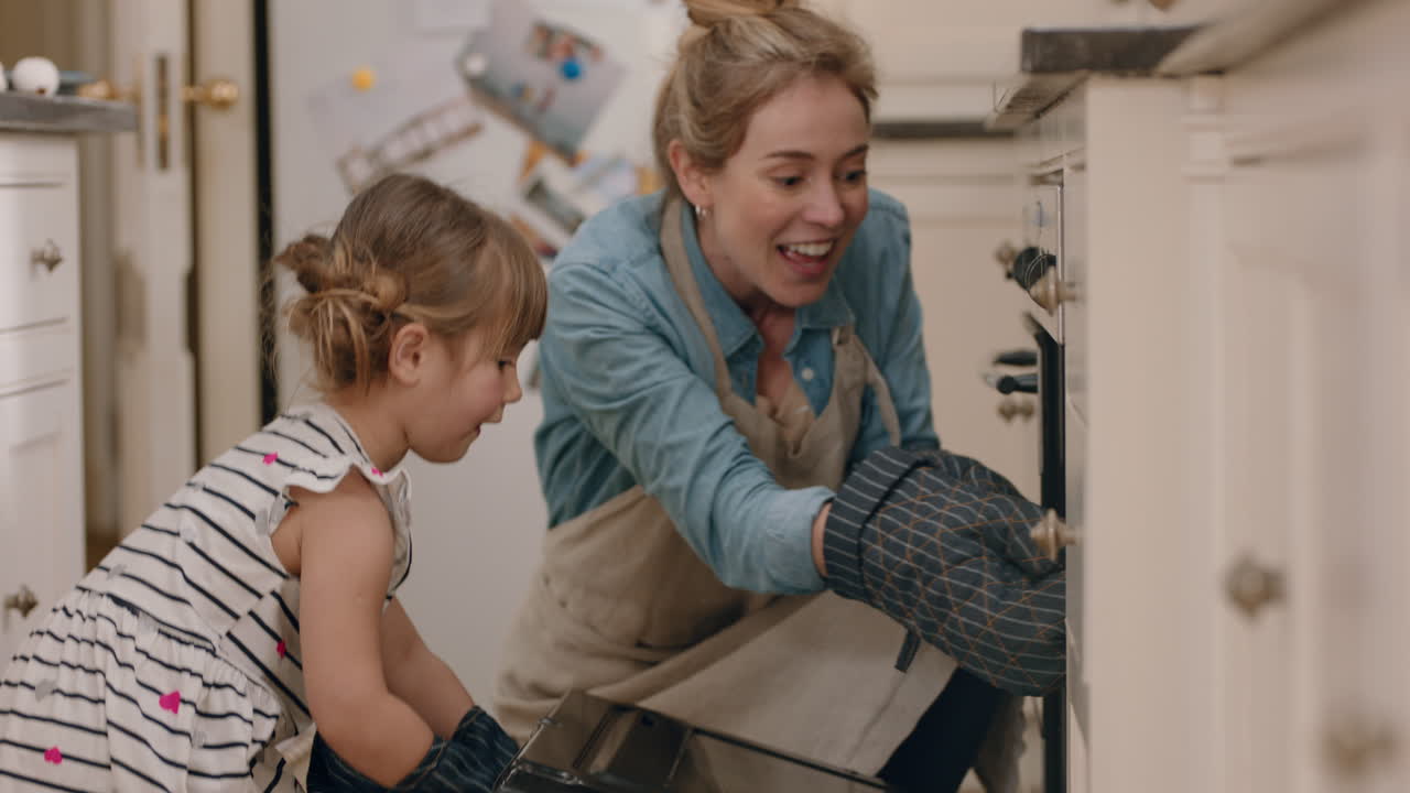 niña feliz ayudando a su madre a hornear en la cocina sacando pastelitos caseros del horno usando guantes de horno disfrutando de deliciosas golosinas frescas