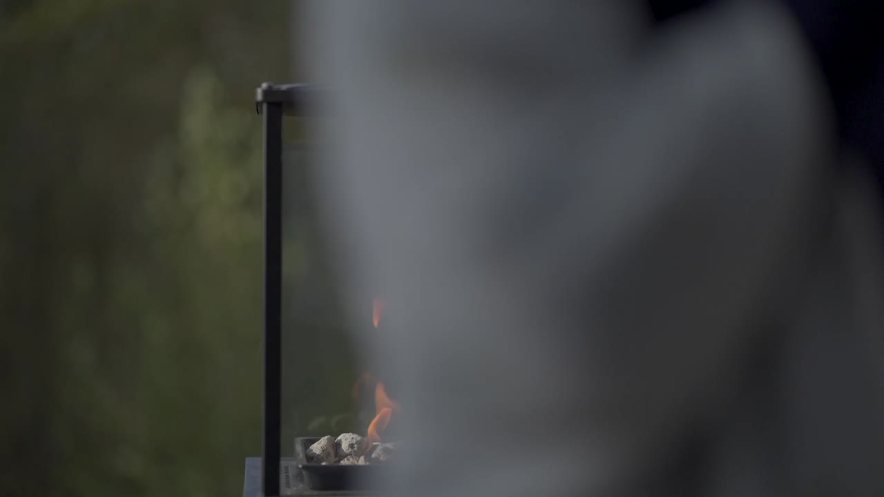 Contemporary glass fire pit with flickering flames over stones in a natural setting