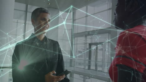 animation of network of connections against two diverse businesswomen discussing at office