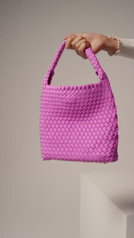 Close-Up-Vertical-Video-Of-Female-Social-Media-Influencer-Producing-User-Generated-Content-Holding-Out-Purple-Fashion-Bag-1