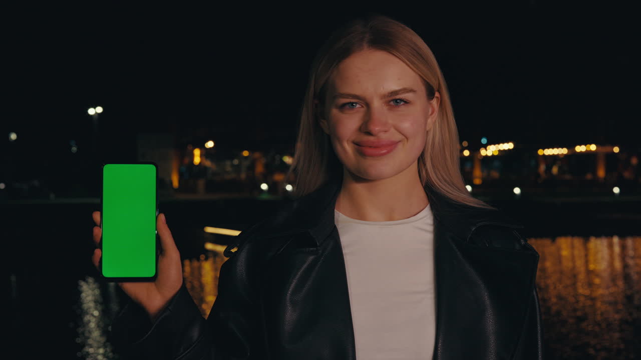 Donna che tiene in mano uno smartphone con schermo verde di notte