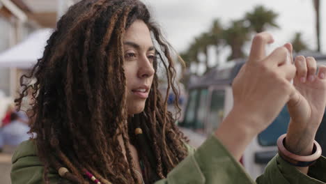 retrato de una hermosa mujer hispana con rastas usando un teléfono inteligente tomando fotos en vacaciones