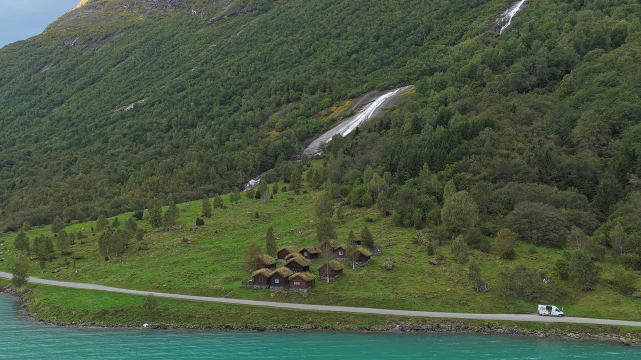 Rustikke hytter ved Lovatnet med majestetiske fjell i bakgrunnen, Norge