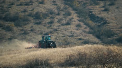 vista teleobjetiva de la regla de los tercios de un tractor arando un campo en un día cálido y soleado con una colina al fondo