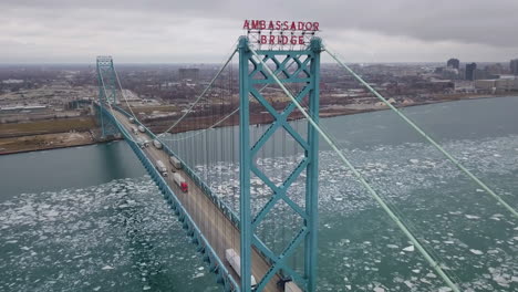 transport trucks driving on the ambassador bridge with detroit in the background